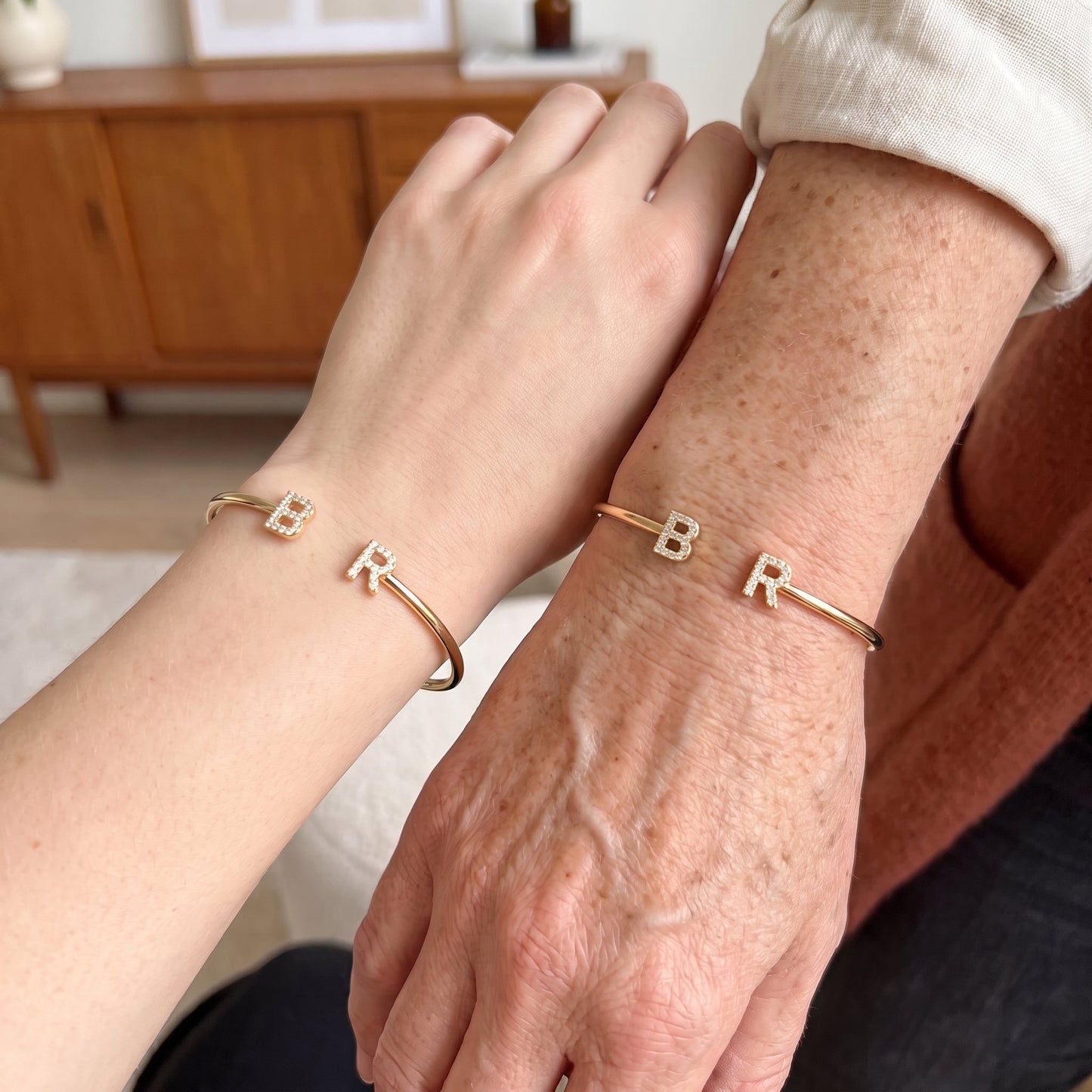 Handen van moeder en dochter met initialen armbanden