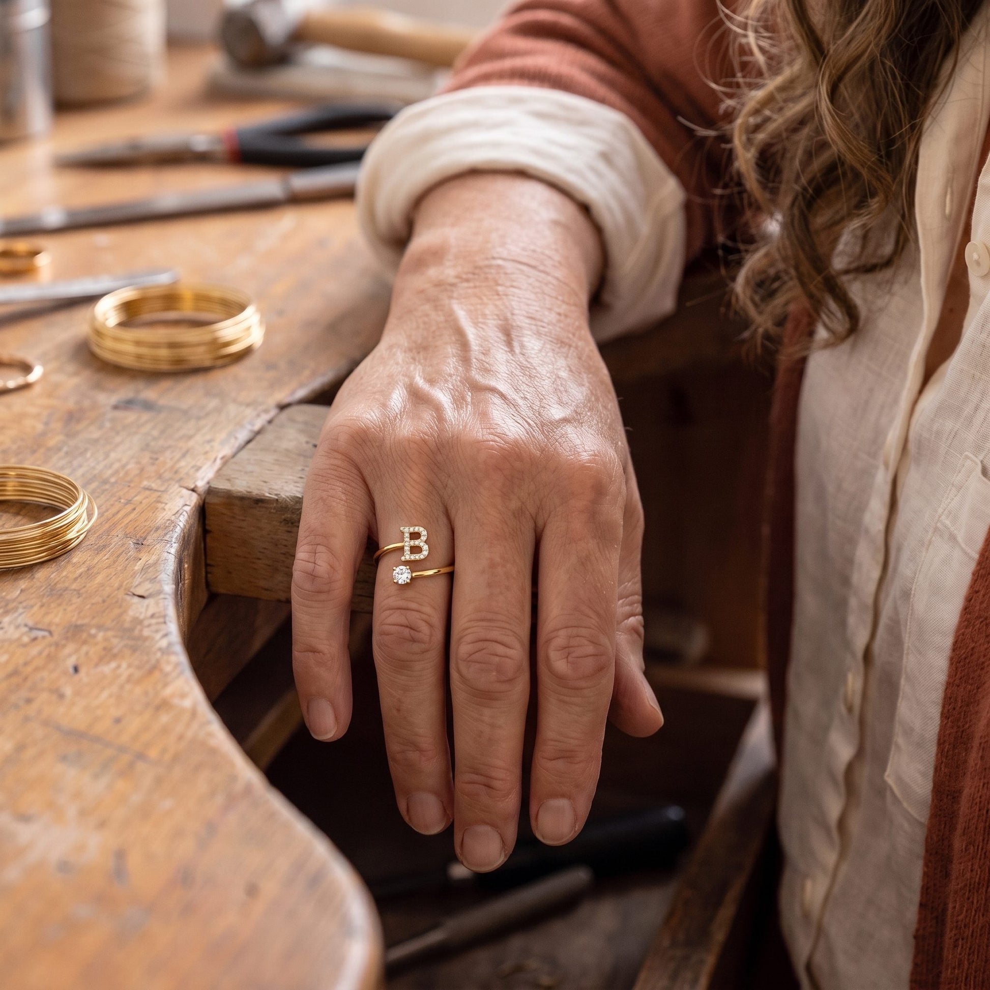 Handgemaakte initiaal- en steenring in goud, gedragen aan de hand