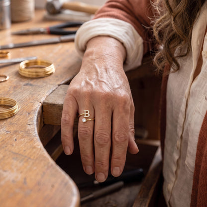 Handgemaakte initiaal- en steenring in goud, gedragen aan de hand
